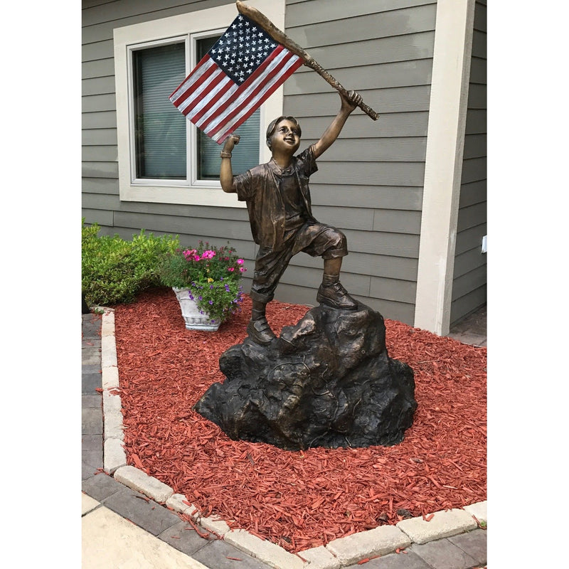 patriotic bronze statue of boy  holding the american flag