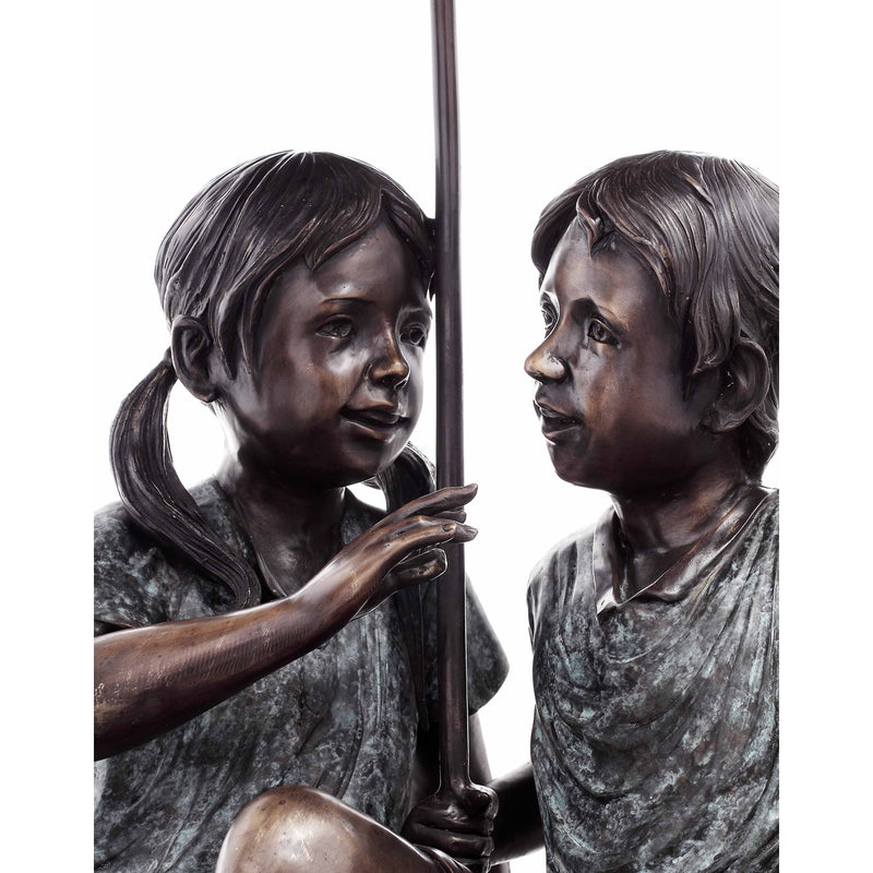 bronze statue of boy and girl under umbrella fountain