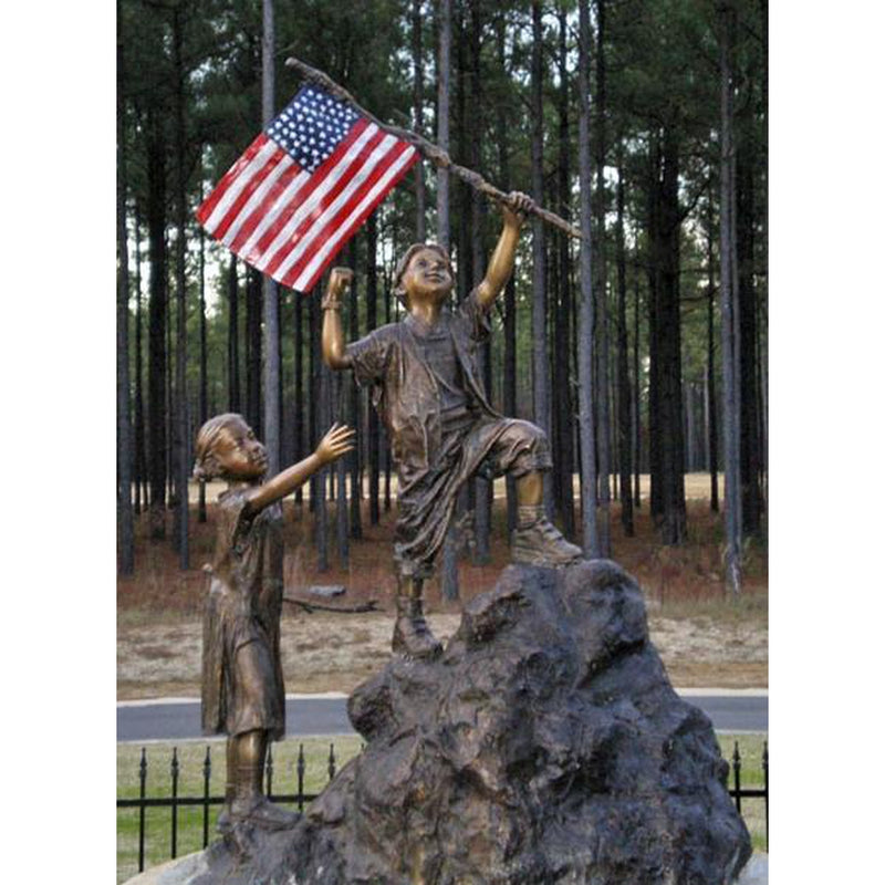 patriotic bronze statue of children holding the american flag