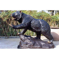 bronze sculpture of bear walking on rock
